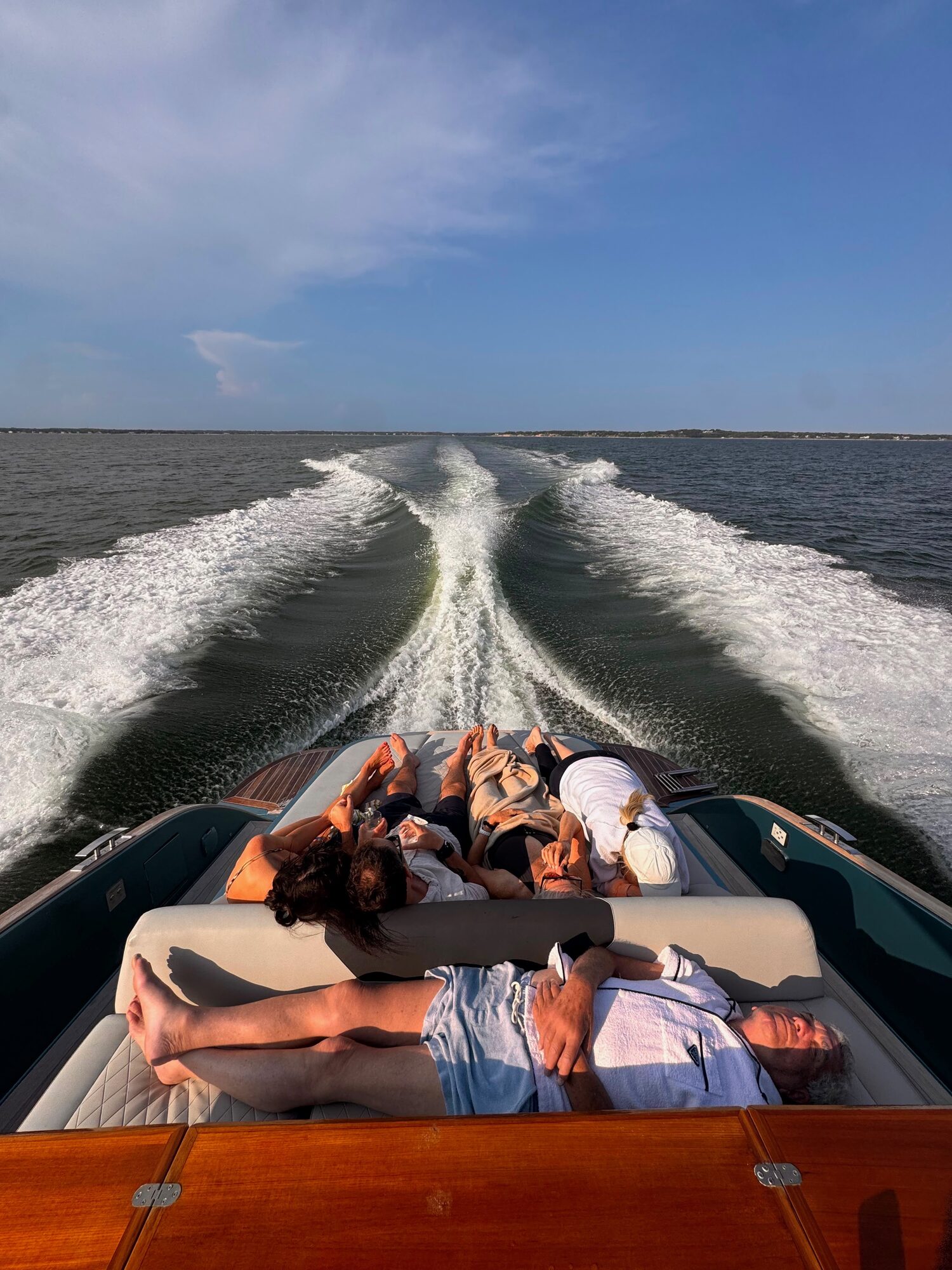 Guests relaxing on the aft sun pad with the wake trailing behind in the Hamptons