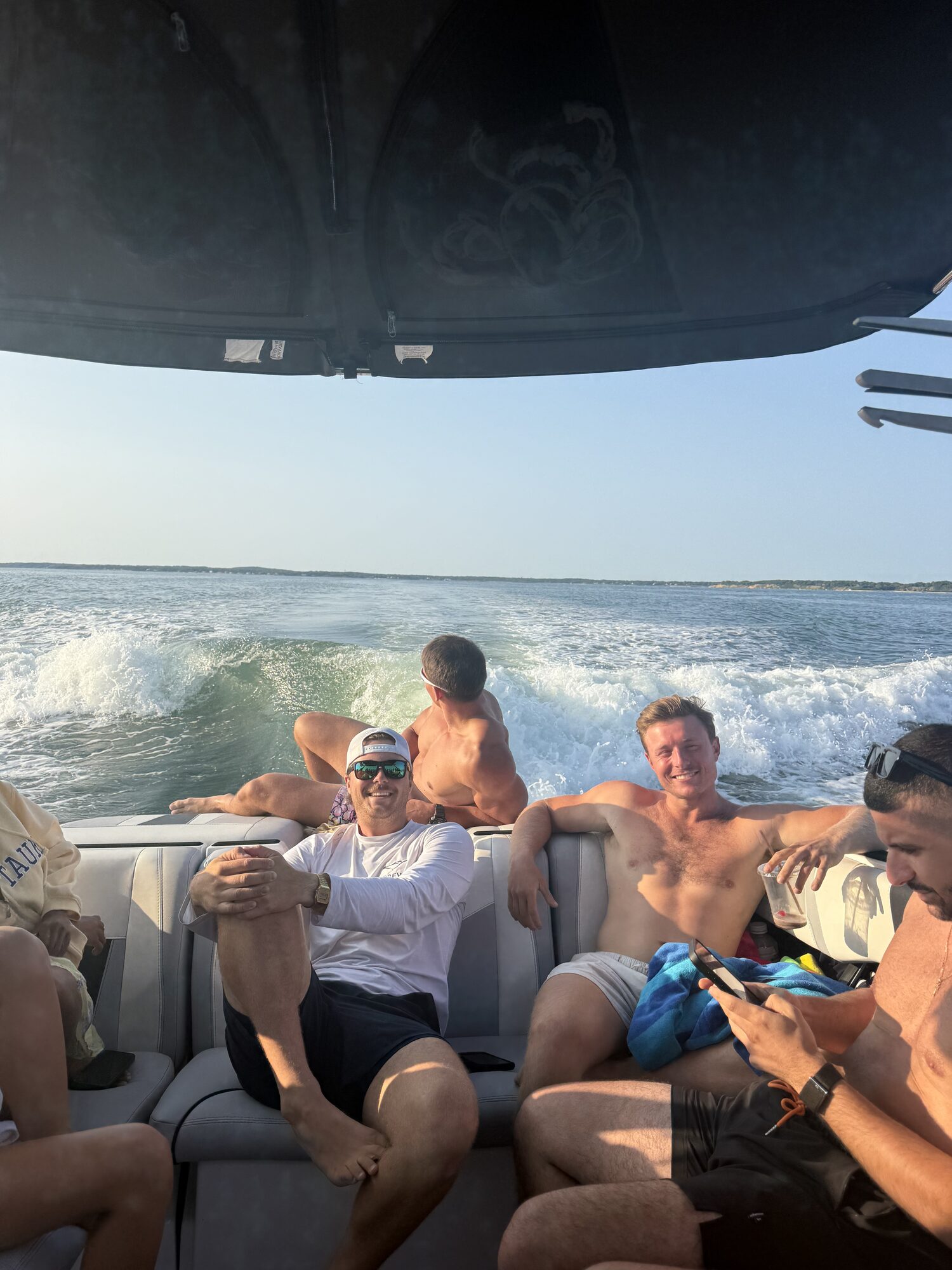 Friends in the cockpit with the wake trailing behind on a Hamptons cruise