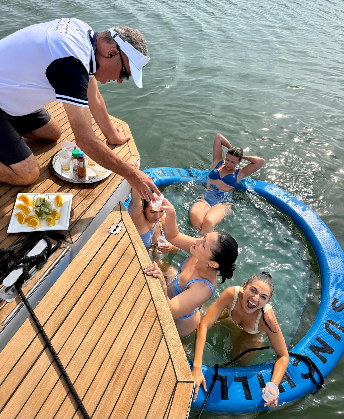 Crew serving drinks to guests in the floating pool off the swim platform