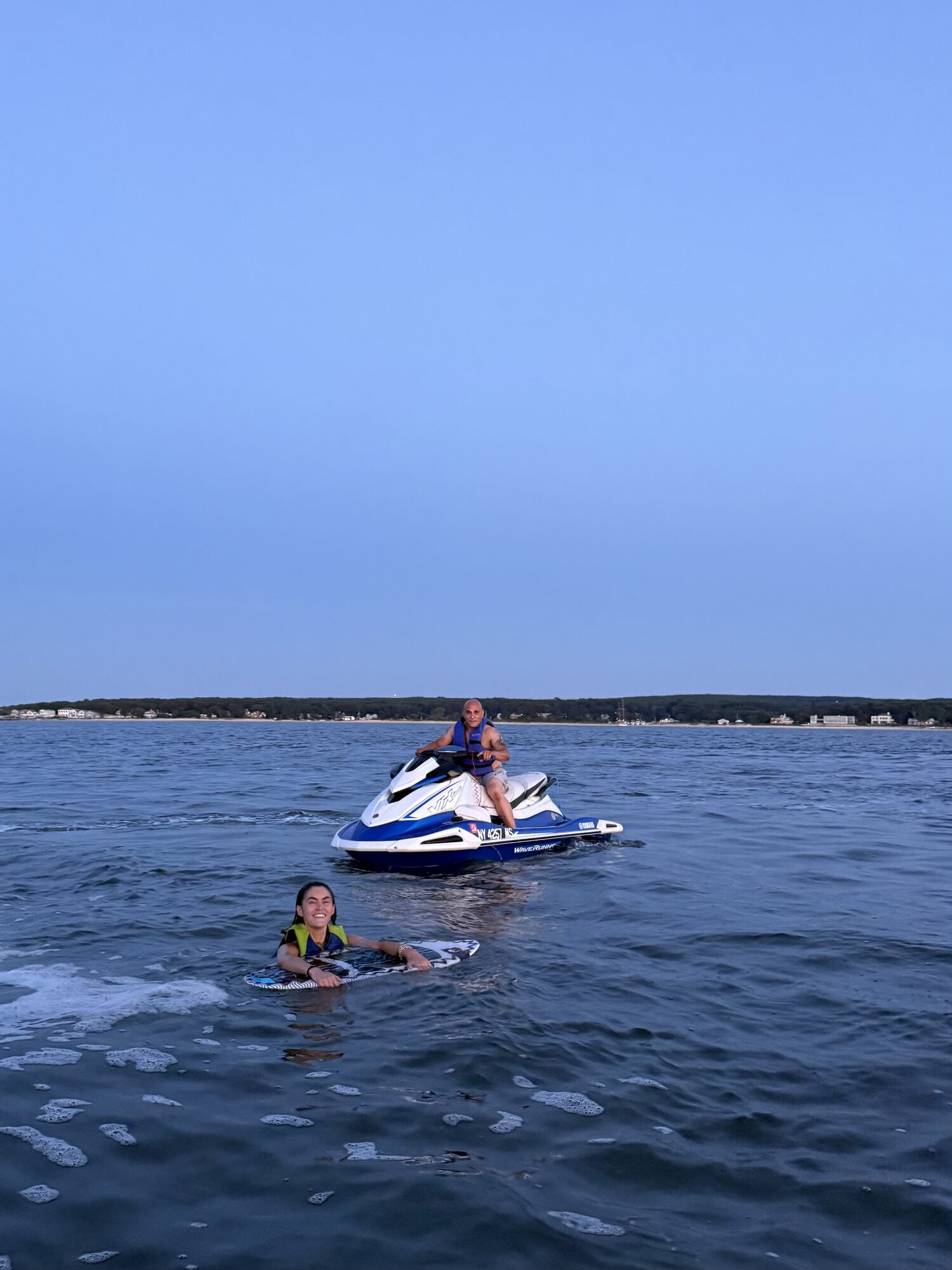 Guests riding a jet ski alongside a Yacht Hampton charter in the Hamptons