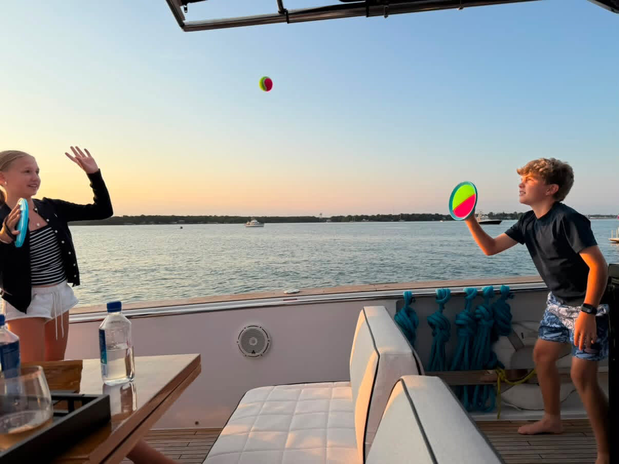 Kids playing paddle ball on the aft deck at sunset