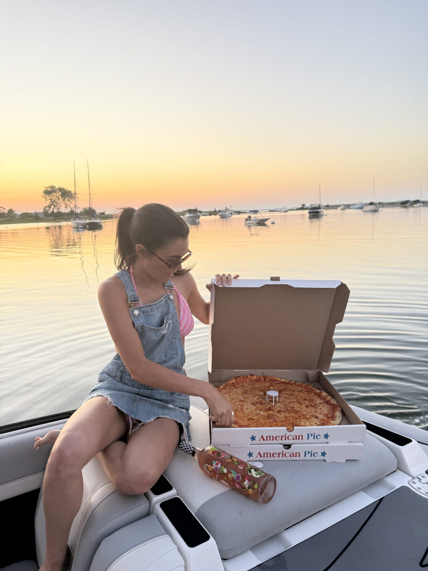 Guest with a fresh pizza on the bow at sunset during a Hamptons charter